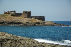 an old castle sitting on top of a cliff next to the ocean