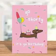 a pink card with a dog holding a birthday cake and balloons on it's back