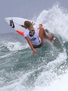 a woman riding a wave on top of a surfboard