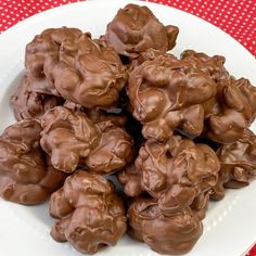 a white plate topped with lots of chocolate covered candies on top of a red and white checkered table cloth