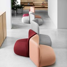 several different colored chairs sitting in a room next to a counter and planter on the floor