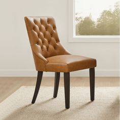 a brown chair sitting on top of a rug in front of a white wall and window