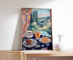 a painting is hanging on the wall above a table with plates and cups in front of it