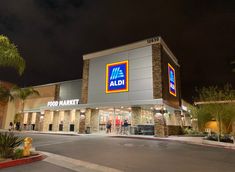 an aldi store at night with people walking in front