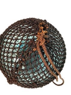 a blue and brown netted ball with rope on it's end, sitting in front of a white background