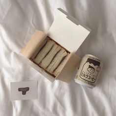 an open box with slices of cake next to a can of tea on a bed