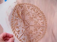 a person is working on an intricately designed piece of paper with wood carving in the shape of a heart