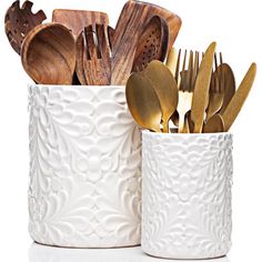 wooden utensils and spoons are in a white cup on a white surface