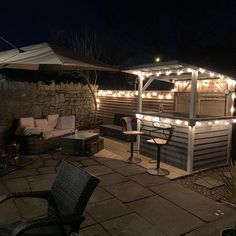 an outdoor bar with lights on the roof and patio furniture in the background at night