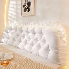 a white bed with ruffles on it and an open book laying next to it