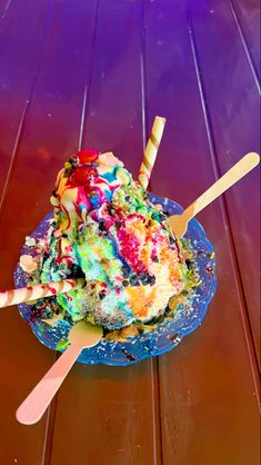 a blue bowl filled with ice cream and colorful toppings on top of a wooden table