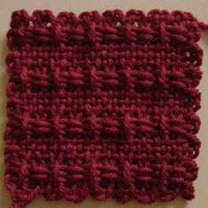 a crocheted piece of red yarn on a white surface