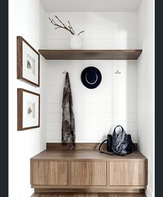 a hat, coat rack and purse on a wooden shelf in a white walled entryway