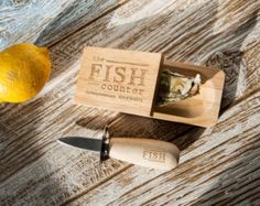 a knife and some food in a box on a wooden table next to a lemon