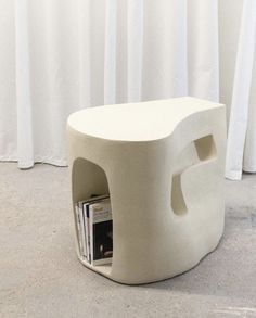 an unusual white stool with magazine holders on it