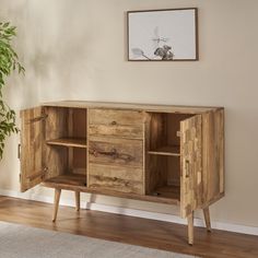 a wooden cabinet sitting on top of a hard wood floor next to a potted plant