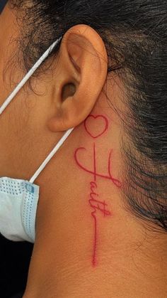 a woman with a tattoo on her neck has a cross and heart behind her ear