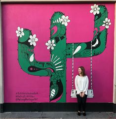 a woman standing in front of a mural on the side of a building