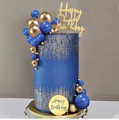 a blue and gold birthday cake with balloons