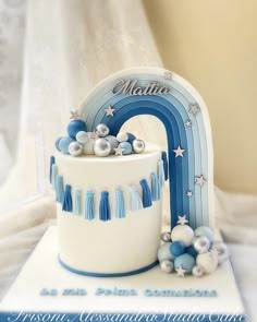 a blue and white birthday cake with a rainbow decoration