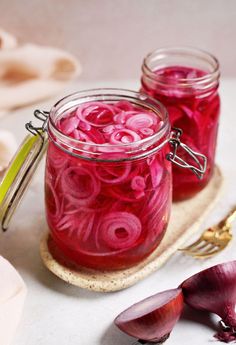 two jars filled with red onions on top of a table