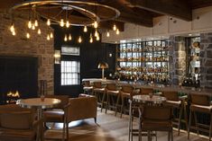 a bar with lots of bottles on the shelves and chairs in front of an open fire place