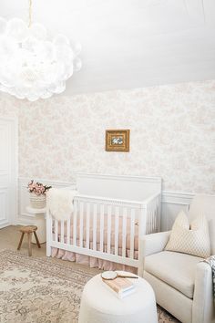 a baby's room with floral wallpaper and white furniture