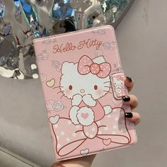 a person holding up a pink hello kitty notebook