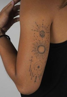 the back of a woman's shoulder with tattoos on her arm and sun, moon and stars