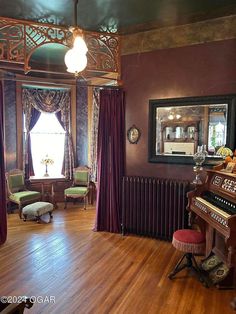 an old fashioned living room with wood floors and purple walls