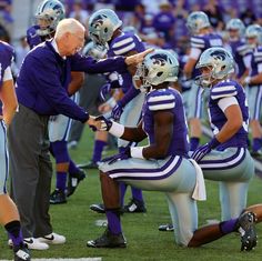 the coach is giving instructions to his team on the sideline during a football game