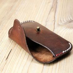 a brown leather case with a button on the inside is sitting on a wooden surface