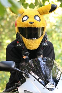 a person wearing a yellow pikachu mask on top of a motorcycle