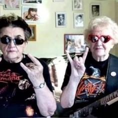 two women sitting on a couch with their fingers up in the air and one holding a guitar