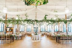 an indoor venue with tables and chairs covered in greenery