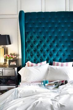 a blue headboard in a bedroom with white sheets and pillows