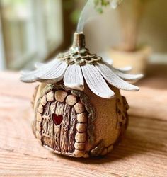 a small house with a flower growing out of it's roof on a table