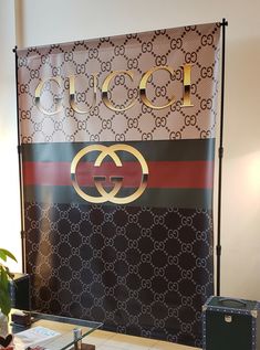 a gucci logo sign on display in front of a table with suitcases and other items