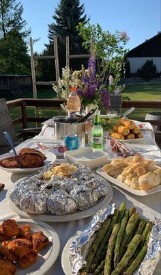 a table full of different types of food on plates and in front of a vase with flowers