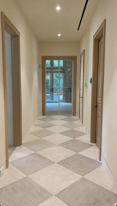 an empty hallway with two doors leading to another room and the floor is tiled in white