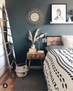 a bed room with a neatly made bed next to a ladder and pictures on the wall