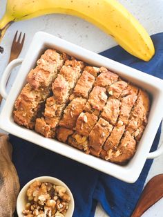 a pan filled with banana bread next to a bowl of nuts