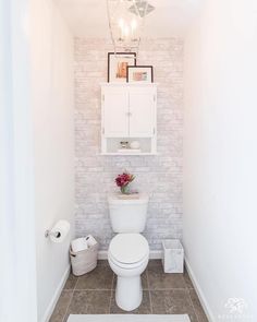 a white toilet sitting in a bathroom next to a wall mounted shelf with pictures on it