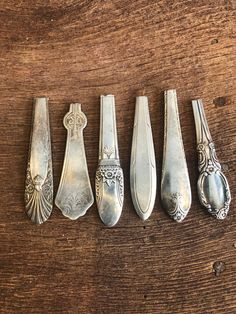 five silver spoons lined up on a wooden table