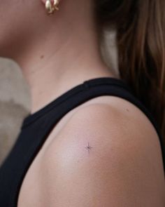 a woman with a small cross tattoo on her upper arm and behind her back shoulder