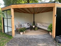 an outdoor living area with couches and potted plants on the ground in front of it