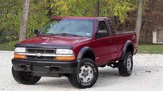 a red pick up truck parked in front of some trees