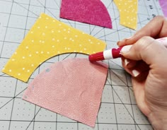 someone is cutting out fabric with scissors on a cutting board, and the paper has been cut