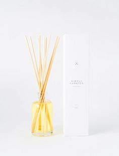 the reeds are in a clear glass vase next to a white box on a white background