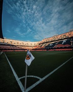 an empty soccer field with a flag on the sideline and sky in the background